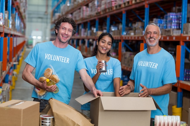 Três voluntários embalando comestíveis em caixa de papelão