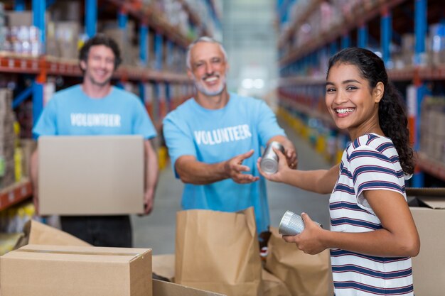 Tres voluntarios empacando comestibles en una caja de cartón