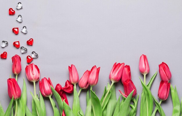 Treze tulipas vermelhas com corações vermelhos no feriado da primavera internacional Dia da Mulher Tulipas dispostas em fundo cinza em linha Dia das Mães conceito cartão de saudação cópia de fundo espaço vista superior