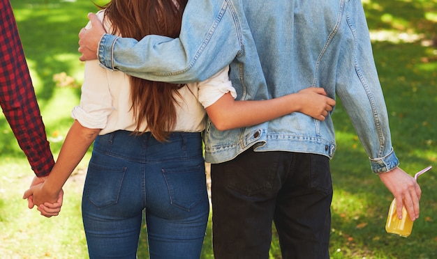 triángulo amoroso. Amistad juvenil y celos. adulterio o poligamia. mujer y dos hombres tomados de la mano