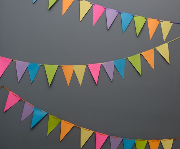 Triángulo colorido banderas de fiesta de bricolaje en una cuerda de una pared gris oscuro