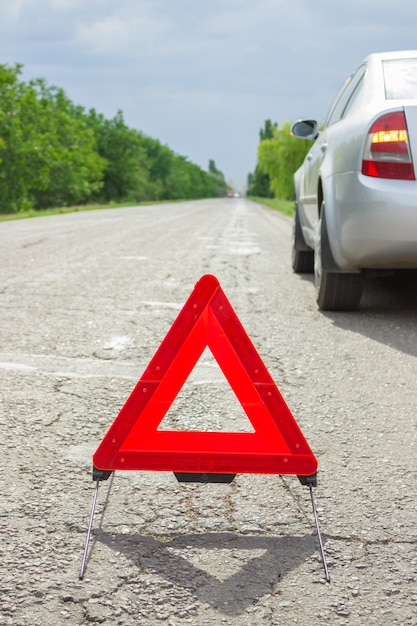 Triángulo rojo de un coche en la carretera. Avería del coche con mal tiempo.