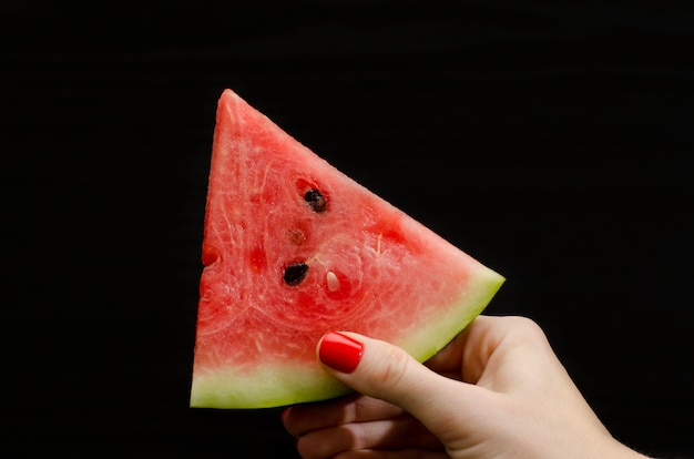 El triangulo de sandia en una mano femenina