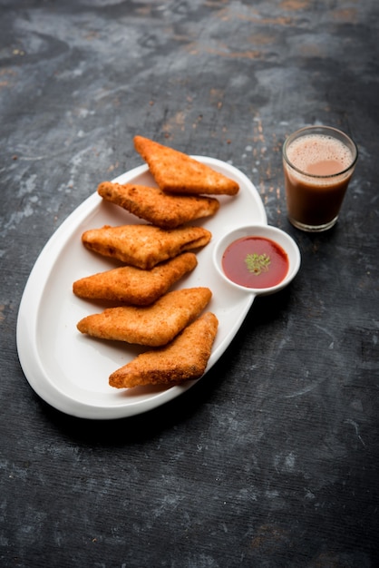 Triângulos de batata crocante ou batata vada cobertos com migalhas de pão e depois fritos. servido com ketchup de tomate. foco seletivo