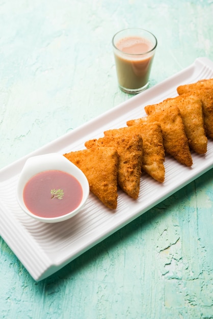 Triângulos de batata crocante ou batata vada cobertos com migalhas de pão e depois fritos. servido com ketchup de tomate. foco seletivo