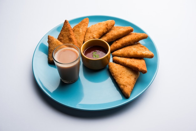 Triángulos de papa crujiente o batata vada cubiertos con pan rallado y luego fritos. servido con salsa de tomate. enfoque selectivo