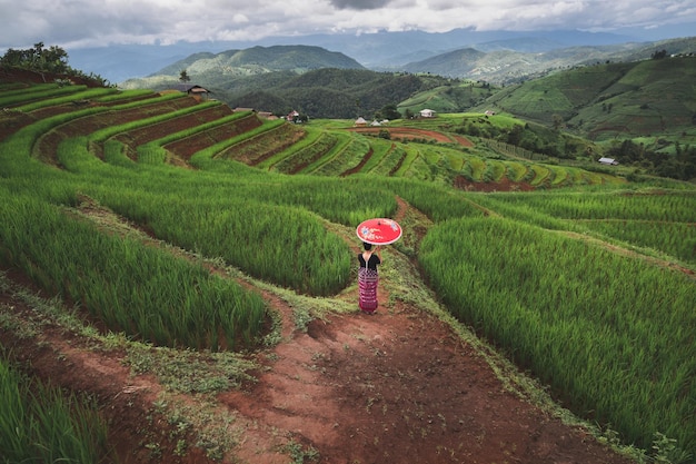 Foto tribu de la colina de la mujer que sostiene el paraguas rojo con el fondo del paisaje de la terraza del arroz