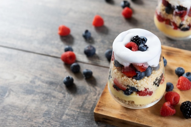 Trifle-Dessert mit Beeren und Sahne auf Holztisch