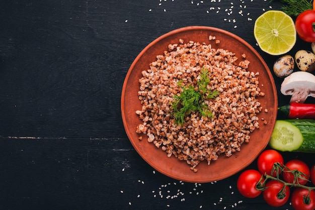 Trigo sarraceno em um prato com legumes frescos Em um fundo de madeira Vista superior Copie o espaço