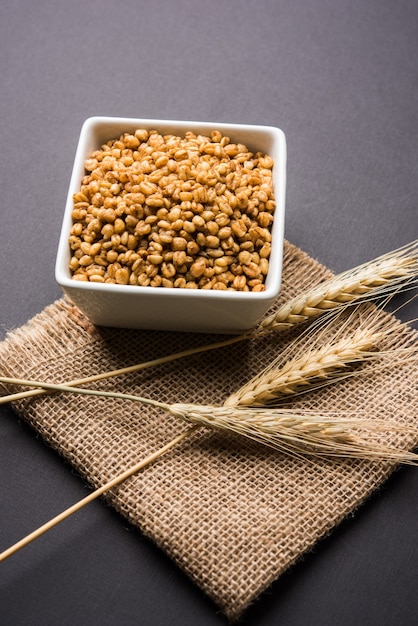 Foto trigo torrado crocante - suplemento dietético indiano, servido em uma tigela branca sobre um fundo sombrio, com foco seletivo