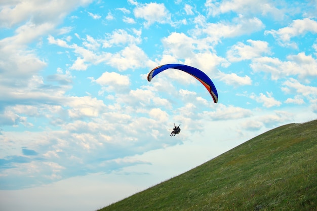 Trike mit einem Fallschirm gegen den blauen Himmel. Gleitschirmfliegen über den Wolken
