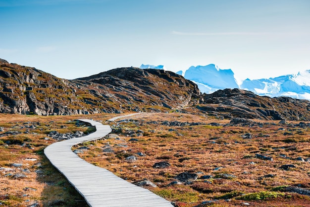 Trilha de caminhada para o fiorde de gelo ilulissat com grandes icebergs ao pôr do sol oeste da groenlândia