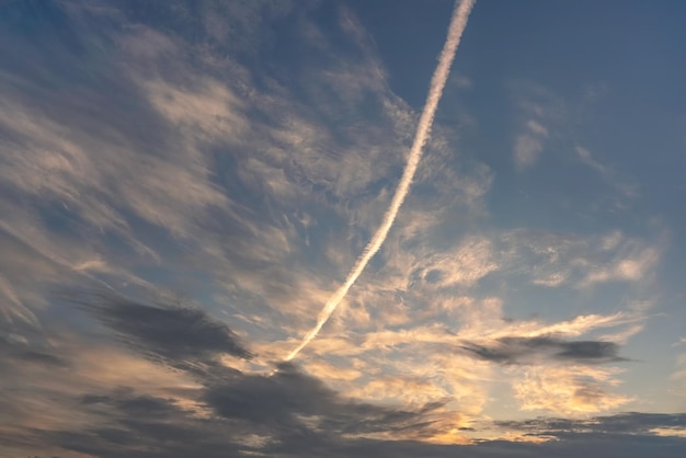 Trilha de condensação rosa branca de avião (também conhecida como chemtrails na teoria da conspiração) pintada na diagonal sobre o céu claro da manhã