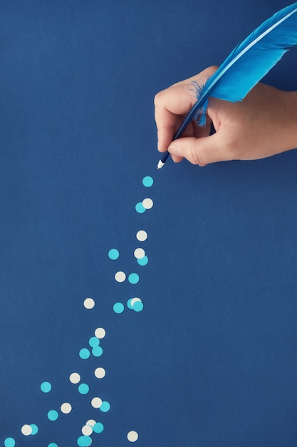 Trilha de desenho de mão feminina de flocos de neve de papel da pena de penas azuis em papel azul escuro