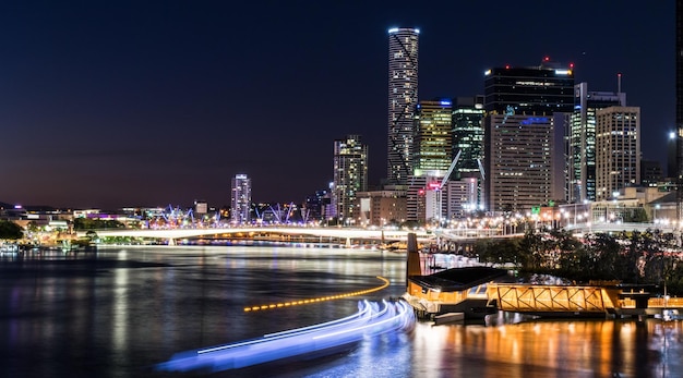 Trilha de luz no rio Brisbane por arranha-céus iluminados contra o céu
