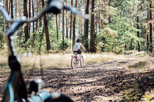 Trilhas de ciclismo de estrada de turismo de bicicleta bicicletas para alugar mulher solteira andando de bicicleta na floresta de pinheiros em