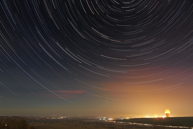 Trilhas de estrelas no céu noturno. uma visão do espaço estrelado no fundo da iluminação da cidade.