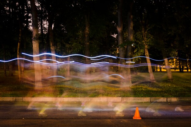 Foto trilhas de luz na estrada por árvores à noite