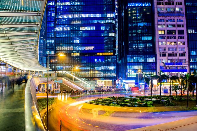 Trilhas de luz na rua da cidade por edifícios à noite