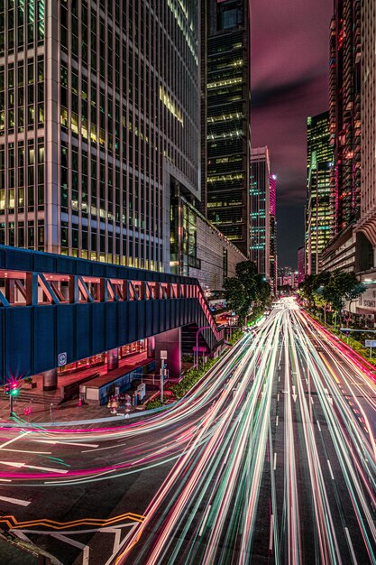 Trilhas de luz na rua da cidade por edifícios à noite