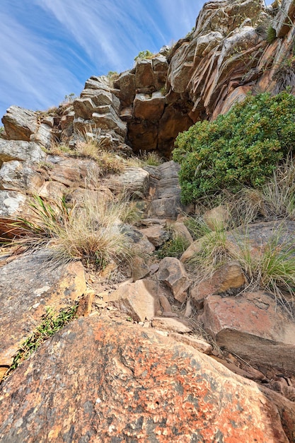 Trilhas de montanha em Lions Head Cape Town África do Sul Trilha rochosa em uma montanha com plantas e grama contra céu azul claro e nublado Ângulo baixo de atração turística em local remoto na natureza