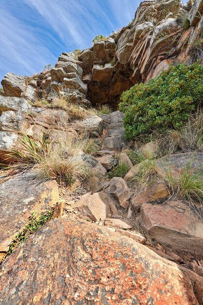 Trilhas de montanha em Lions Head Cape Town África do Sul Trilha rochosa em uma montanha com plantas e grama contra céu azul claro e nublado Ângulo baixo de atração turística em local remoto na natureza