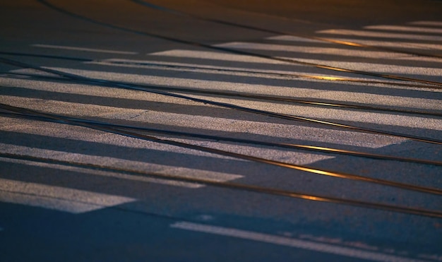 Trilhos de bonde de aço e caminhada branca na estrada de asfalto iluminada por luzes de rua, foto noturna fechada