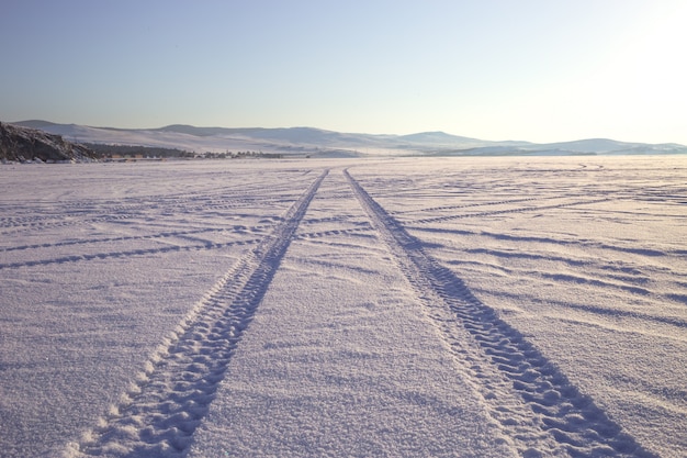 Foto trilhos de roda na estrada de inverno coberta de neve