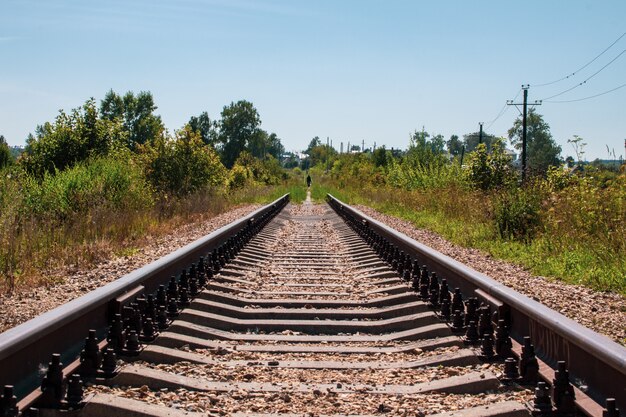 Foto trilhos de trem e cascalho levando para uma distância infinita.