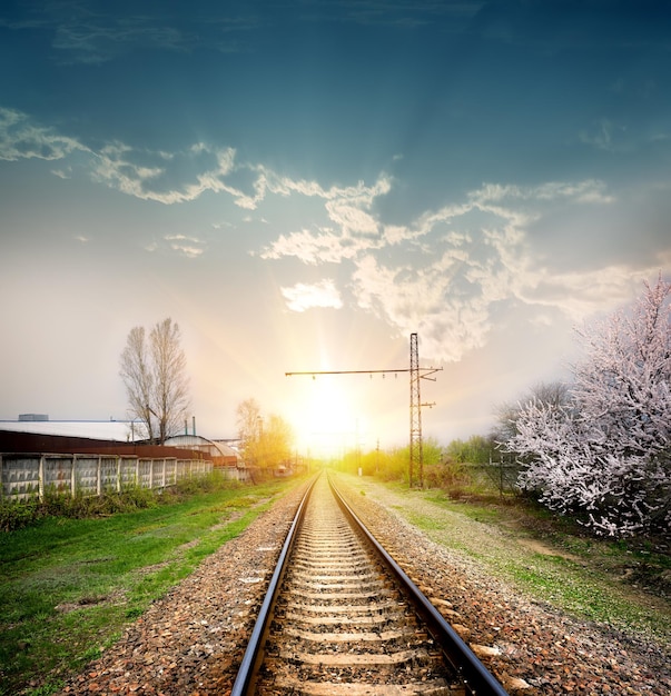 Trilhos de trem em uma cena rural com um belo pôr do sol em tons pastéis