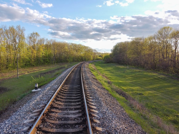 Trilhos ferroviários através do plantio de árvores, grama verde e bela natureza