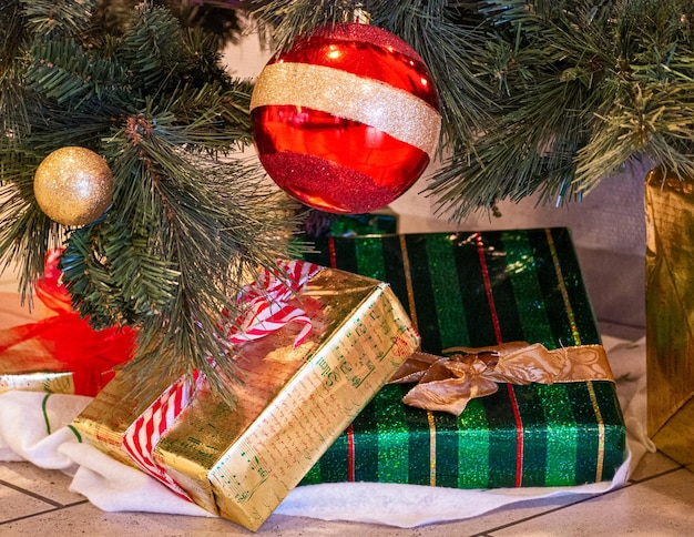 Trineo decorativo de Papá Noel con cajas de regalos de colores debajo del árbol de Navidad