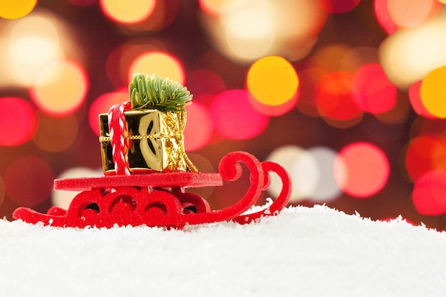 Trineo de Navidad que conduce la caja de regalo de oro y el árbol de Navidad contra el fondo abstracto de la luz del bokeh de la noche