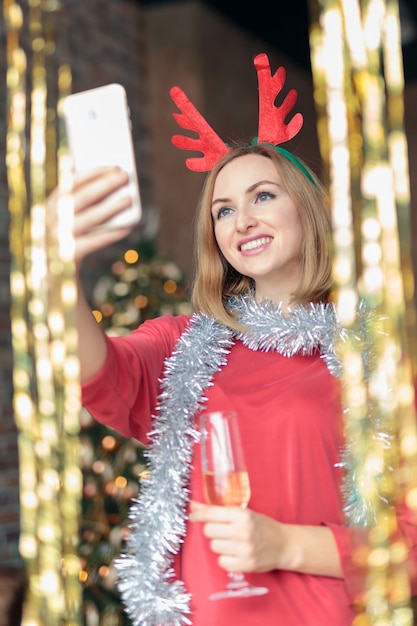 Trinkender Champagner der jungen glücklichen Frau und Nehmen selfie an der Party des neuen Jahres