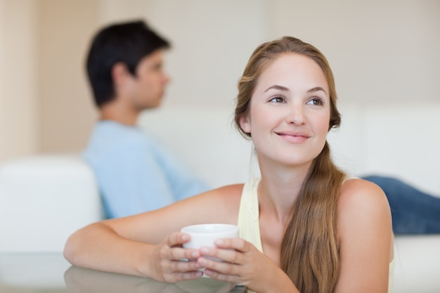 Trinkender Kaffee der Frau, während ihr Verlobtes auf einer Couch sitzt