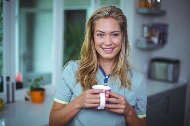 Trinkender Kaffee der jungen Frau bei der Stellung in der Küche