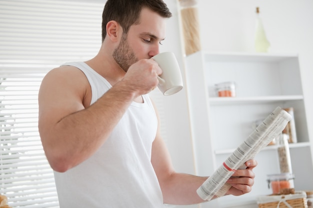 Trinkender Kaffee des jungen Mannes beim Lesen der Nachrichten