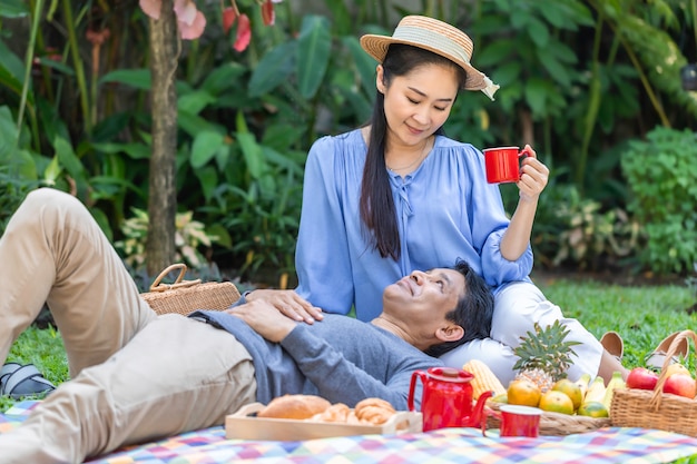 Trinkender Kaffee und Picknick der älteren asiatischen Paare am Garten.