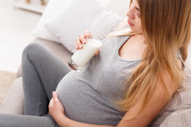 Trinkglas der schwangeren Frau Milchnahaufnahme. Junge erwartungsvolle Blondine, die gesundes Getränk genießt. Gesundheitswesen, Ernährung, Vitamine, Schwangerschaftskonzept