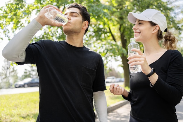 Trinkwasser aus einer Plastikflasche junges Paar Workout-Übung im Freien laufen