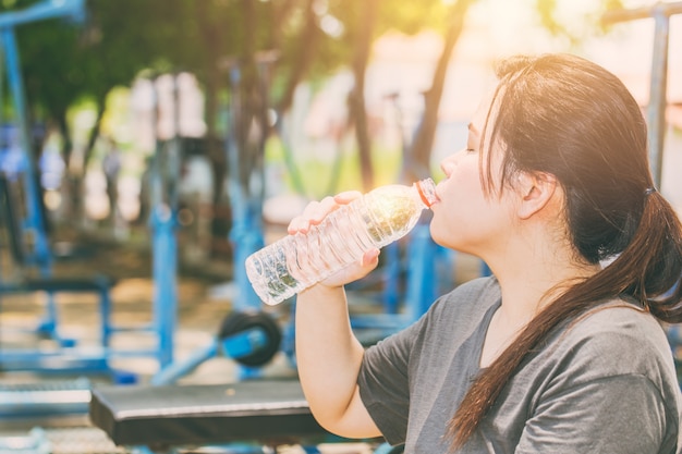 Trinkwasser der Asiatinnen an Übung des heißen Tages im Freien im Park