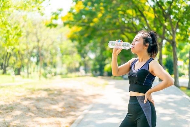 Trinkwasser der asiatischen Frau in der Sportbekleidung