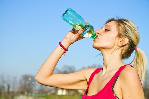 Trinkwasser der Frau von der Flasche nach Eignungssportübung