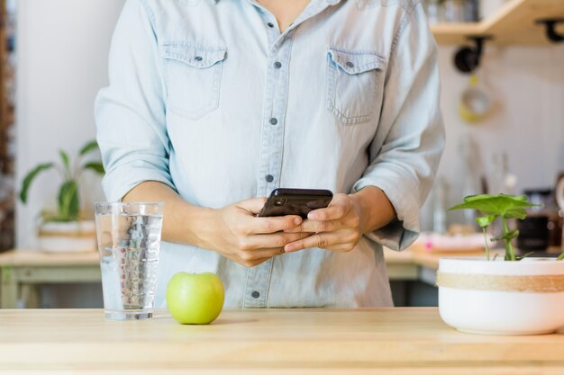 Trinkwasser der Frau, während sie ihr Handy benutzt