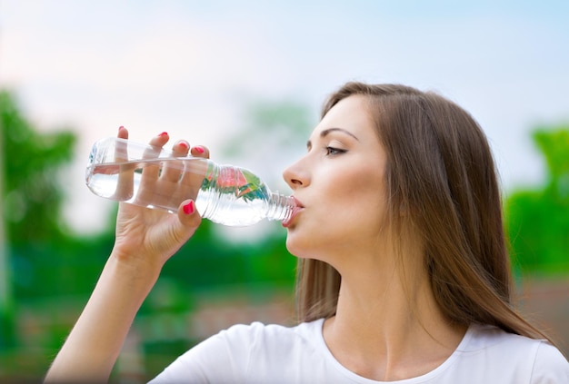 Trinkwasser der jungen attraktiven Frau draußen