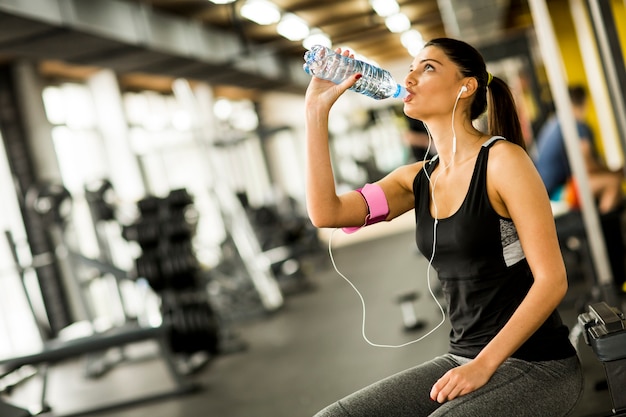 Trinkwasser der jungen Frau des attraktiven Sports beim Sitzen und Stillstehen nach Training