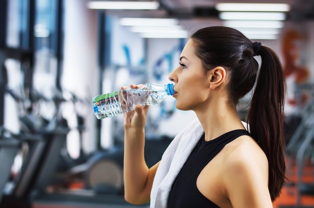 Trinkwasser der jungen frau in der turnhalle