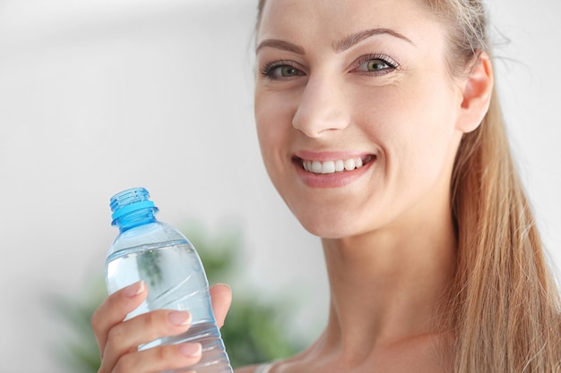 Trinkwasser des schönen Mädchens auf hellem Hintergrund