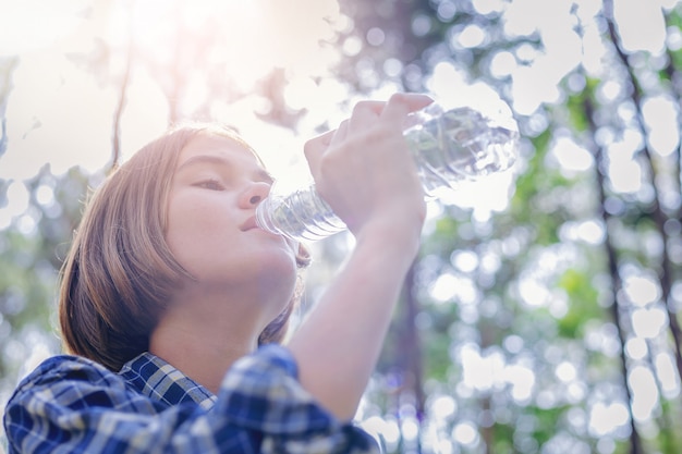 Trinkwasser des schönen Mädchens von der Plastikflasche mit Sonnenaufgang