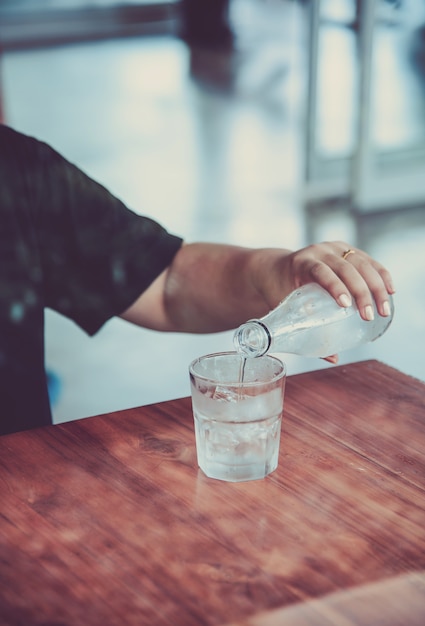 Trinkwasser wird aus einer Flasche in ein Glas gegossen